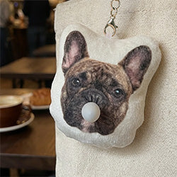 French bulldog Chew Chew Club custom plush keychain with bubble detail attached to a cream tote bag in a cafe
