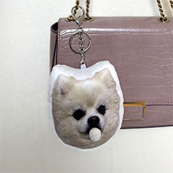 White Pomeranian Chew Chew Club custom plush keychain with bubble detail attached to a pink handbag